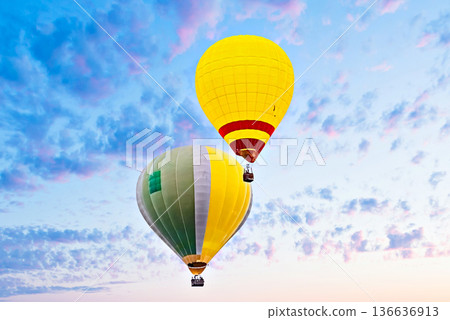 Colorful hot air balloon flying under orange sunset sky Colorful hot air balloon flying under orange sunset sky 136636913