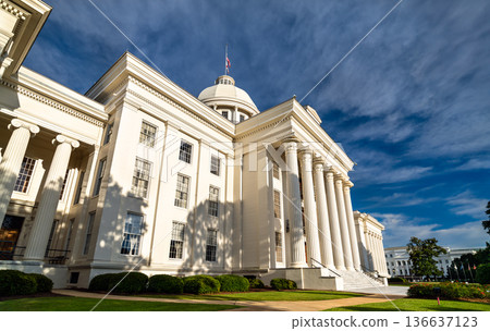 Alabama State Capitol in Montgomery, United States. Greek Revival architecture features a white portico and columns under a blue sky 136637123