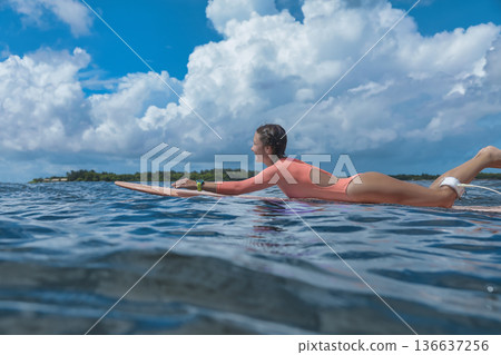 Woman Balances On Ocean Surf, Serene Scene Of Woman Paddling 136637256