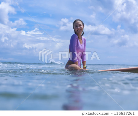 Lively Woman In Violet Clothing Calmly Reclining On Her Surfboard At Dawn Lively Woman In Violet Clothing Calmly Reclining On Her Surfboard At Dawn 136637261