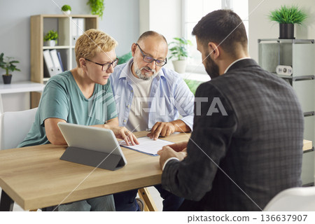 Senior couple signing a contract with advisor during meeting and paperwork review Senior couple signing a contract with advisor during meeting and paperwork review 136637907