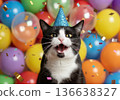 A happy black and white tuxedo cat wearing a blue glitter party hat, celebrating with a joyful expression. The background is filled with colorful blurred balloons and falling confetti 136638327