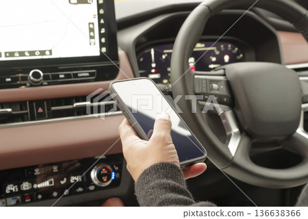 The hand of a man operating a smartphone in the driver's seat The hand of a man operating a smartphone in the driver's seat 136638366