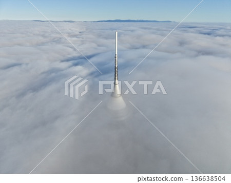 Tall Mast Above Fog, Cinematic Perspective Of Slender Tower Emerging From Dense Fog Under Muted Blue Sky Tall Mast Above Fog, Cinematic Perspective Of Slender Tower Emerging From Dense Fog Under Muted Blue Sky 136638504