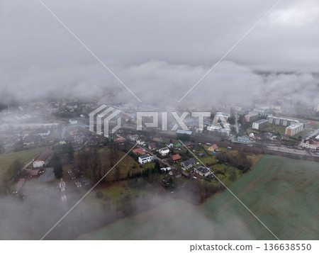 Serene Landscape With Clouds, Misty Aerial Perspective Showcasing Rural Fields And Distant Industry 136638550