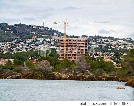 Construction Site Depicting Growth Of City Infrastructure Against Natural Background Of Water And Mountains 136638671