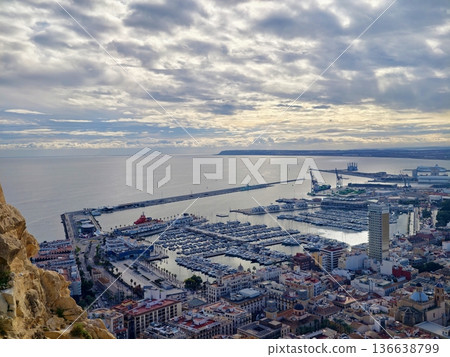 Dramatic Aerial Perspective Of Peaceful Seaside Port Illuminated By Golden Light And Cloudy Skies 136638799