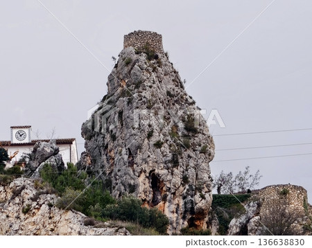 Majestic Mountain Watchtower, Vertical Stone Obelisk Soaring Above Rural Rooftops And Paths 136638830