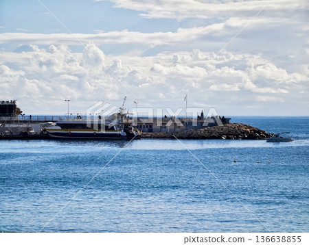 Tranquil Seascape With Lighthouse, Calm Harbor Surroundings Featuring Distant Lighthouse And Patrol Boat Tranquil Seascape With Lighthouse, Calm Harbor Surroundings Featuring Distant Lighthouse And Patrol Boat 136638855