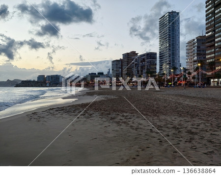 Evening At Bustling City Beach Showing Illuminated Buildings And Peaceful Shoreline Activities Evening At Bustling City Beach Showing Illuminated Buildings And Peaceful Shoreline Activities 136638864