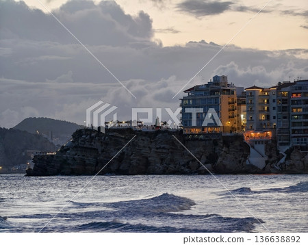 Bayside Cliff Town Illuminated By Flickering Lights Amid Turbulent Waves And Romantic Evening Scenes 136638892