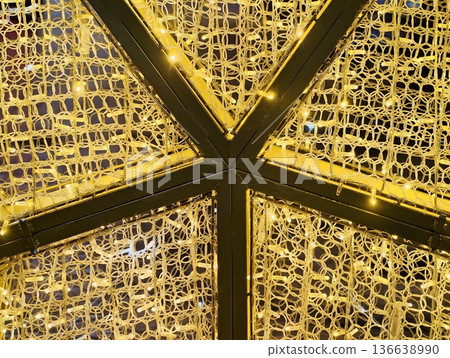 Elegant Geometric Framework Hosting Glowing Mesh With Artisanal Metallic Threads And Miniature Bulbs Elegant Geometric Framework Hosting Glowing Mesh With Artisanal Metallic Threads And Miniature Bulbs 136638990