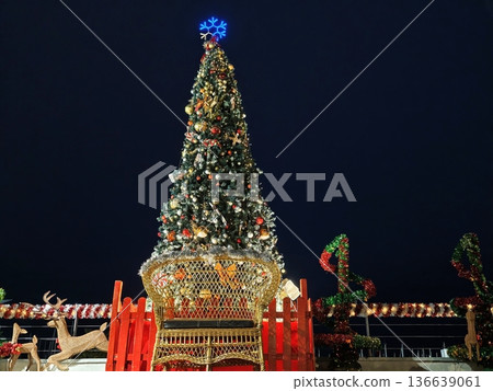 Elegant Christmas Tree Illuminated Beside Water Amid Glowing Market Lights And Joyful Gatherings Elegant Christmas Tree Illuminated Beside Water Amid Glowing Market Lights And Joyful Gatherings 136639061