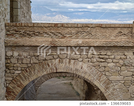 Gateway Opens To Scenic Mountains, Ancient Stone Archway Crowns Distant Mountain Ranges And Moody Skies Gateway Opens To Scenic Mountains, Ancient Stone Archway Crowns Distant Mountain Ranges And Moody Skies 136639083