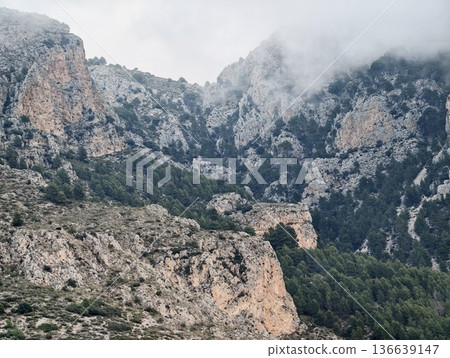 Eroded Rock Formations Beneath Overcast Clouds, Vast Valley With Layered Rocks And Distant Mountain Ridges Eroded Rock Formations Beneath Overcast Clouds, Vast Valley With Layered Rocks And Distant Mountain Ridges 136639147