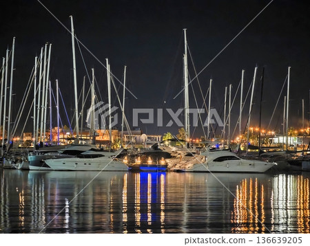 Vibrant Maritime Scene, Boats Rest Under Shimmering Lights, Harbor Filled With Bustling Activity At Night 136639205