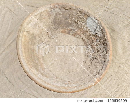 Weathered Bowl Scene, Sunlit Scene Depicting Aged Terracotta Vessel Amidst Shells And Sand At Coast 136639209