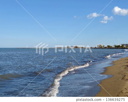 Calm Beach Scene, Tranquil Seaside Landscape Featuring Soft Sunlight And Distant Buildings 136639275