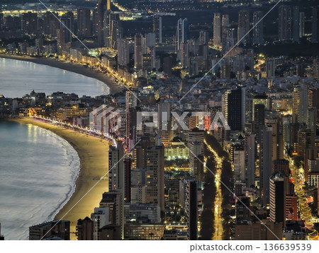 Shoreline Street Illuminated Under Night Sky, Bright Coastal Avenue Reflects City Skyline At Evening 136639539
