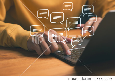 Online communication and chat concept showing hands typing on laptop with digital message icons, representing social media, instant messaging, customer support, and digital conversation technology. 136640226