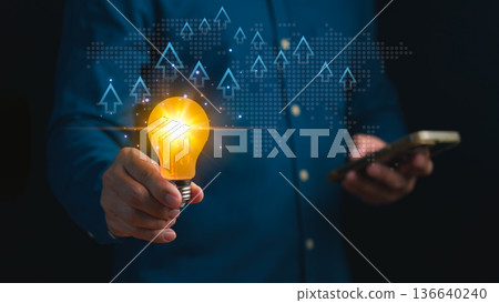 Innovation and business growth concept showing person holding glowing light bulb with rising arrows and digital world map, symbolizing creativity, success, and global development. 136640240