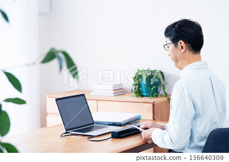 Hands of a man preparing to file his tax return Hands of a man preparing to file his tax return 136640309