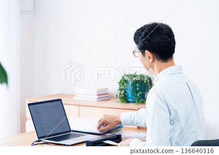 Hands of a man preparing to file his tax return Hands of a man preparing to file his tax return 136640316