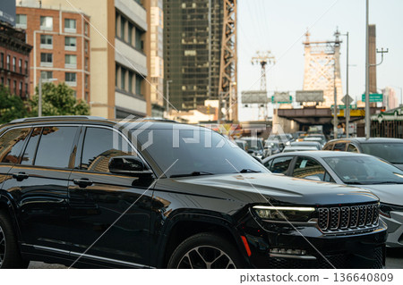 A black SUV is seen in heavy traffic on a New York City street. The Queensboro Bridge and city buildings are visible in the background during rush hour. A black SUV is seen in heavy traffic on a New York City street. The Queensboro Bridge and city buildings are visible in the background during rush hour. 136640809