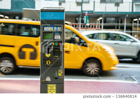 A close-up view of a parking meter in New York City as a yellow taxi speeds past. The motion blur emphasizes the fast pace of city life against the static meter. A close-up view of a parking meter in New York City as a yellow taxi speeds past. The motion blur emphasizes the fast pace of city life against the static meter. 136640814