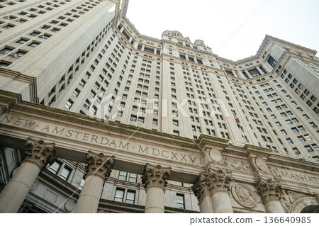 Close-up view of the grand entrance to the Manhattan Municipal Building in New York City. The inscription New Amsterdam MDCXXV and tall stone columns highlight the building's classical architecture. Close-up view of the grand entrance to the Manhattan Municipal Building in New York City. The inscription New Amsterdam MDCXXV and tall stone columns highlight the building's classical architecture. 136640985