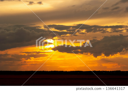Dramatic orange sunset light in the sky over autumn prairies. 136641317