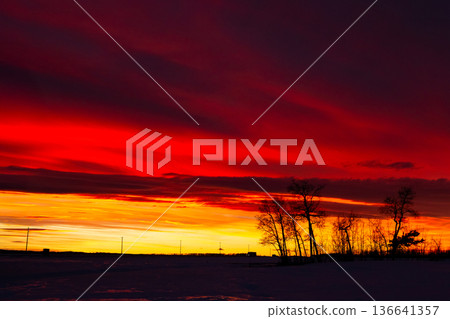 Colorful red and orange sunset sky in winter prairies. Colorful red and orange sunset sky in winter prairies. 136641357