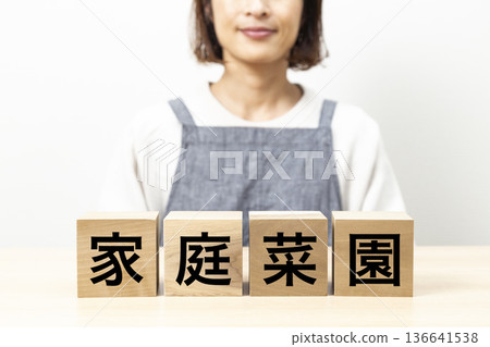 A woman wearing an apron and a block with the words "Vegetable Garden" written on it A woman wearing an apron and a block with the words "Vegetable Garden" written on it 136641538
