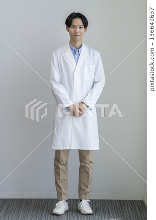 A man in his 30s wearing a white coat smiling at the camera, full body, white background, portrait A man in his 30s wearing a white coat smiling at the camera, full body, white background, portrait 136641637