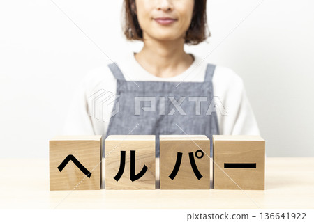 一位身穿圍裙、手持寫有「幫手」字樣積木的女士 136641922