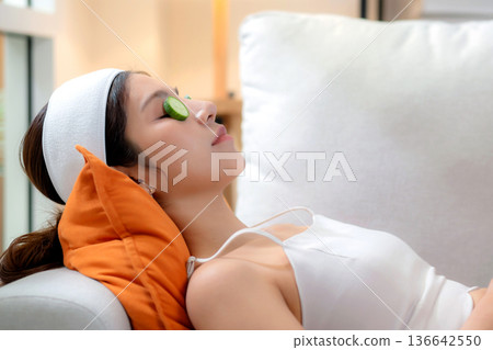 Beauty young asian woman relax on sofa with cucumber eye mask in living room. 136642550