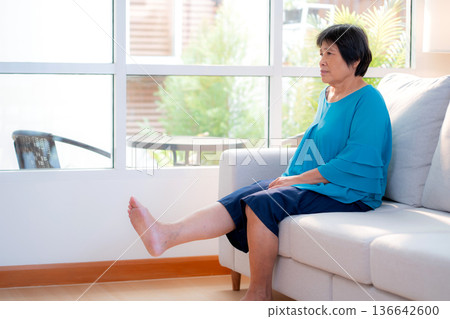 Senior asian woman practice stretch leg for treatment knee pain sitting on sofa in living room. Senior asian woman practice stretch leg for treatment knee pain sitting on sofa in living room. 136642600