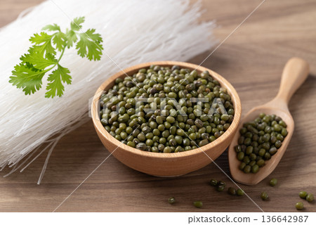 Mung beans seeds in a wooden bowl and dried glass noodles, raw ingredients for Thai vermicelli Mung beans seeds in a wooden bowl and dried glass noodles, raw ingredients for Thai vermicelli 136642987