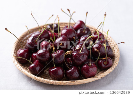 Fresh red cherries with water droplets in a basket on a cotton fabric background, Healthy fruit 136642989