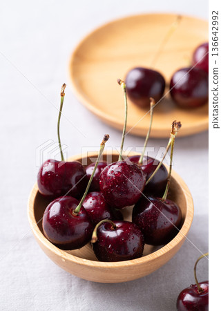 Fresh red cherries with water droplets in a wooden bowl 136642992