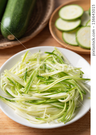 Fresh zucchini noodles (zoodles) in a white plate, prepared for healthy cooking Fresh zucchini noodles (zoodles) in a white plate, prepared for healthy cooking 136643015