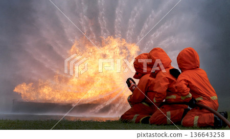 Firefighter Rescue team training in fire fighting extinguisher. Teamwork Firefighter fighting with flame using fire hose chemical water foam spray engine. Fireman teams wear hard hat safety uniform 136643258