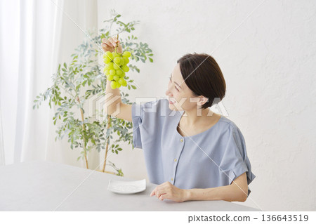 A woman holding Shine Muscat grapes in the living room A woman holding Shine Muscat grapes in the living room 136643519