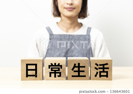身穿圍裙、手持寫有「日常生活」字樣積木的女子 身穿圍裙、手持寫有「日常生活」字樣積木的女子 136643601