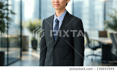 微笑的男商務人士站在辦公室裡 微笑的男商務人士站在辦公室裡 136643949