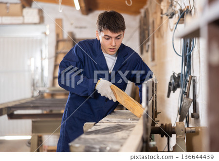 Young man cutting wooden board with circular saw at sawmill Young man cutting wooden board with circular saw at sawmill 136644439