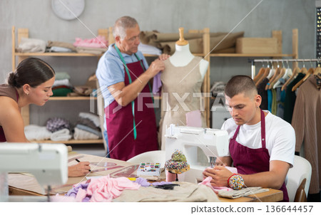 Guy employee sewing, stitch clothes, mature man work with mannequin, girl draw dress pattern Guy employee sewing, stitch clothes, mature man work with mannequin, girl draw dress pattern 136644457