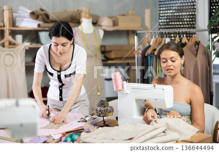 Two female tailors creating custom garments in workshop Two female tailors creating custom garments in workshop 136644494