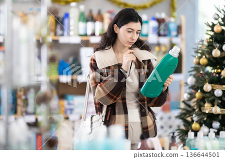 Young woman buyer chooses detergent in decorated store Young woman buyer chooses detergent in decorated store 136644501