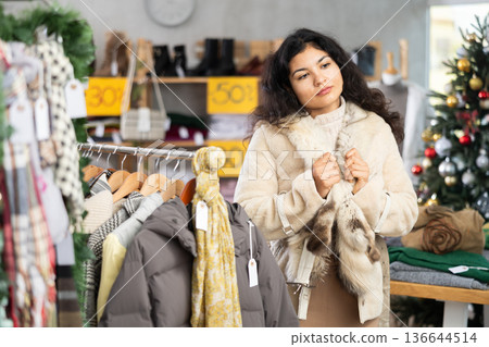 Latina chooses a fur coat in the store 136644514